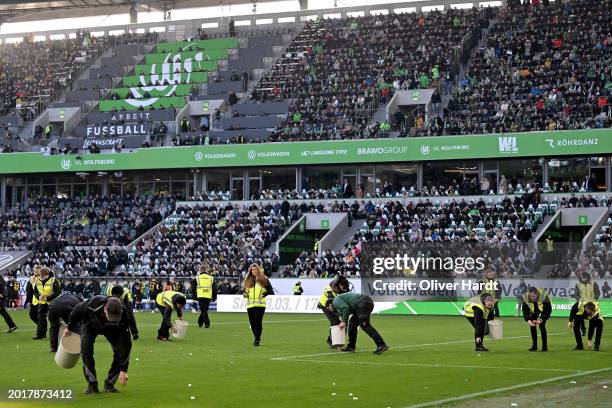 Stewards collect tennis balls thrown onto the pitch by fans in protest of the DFL's investment plans prior to the Bundesliga match between VfL...