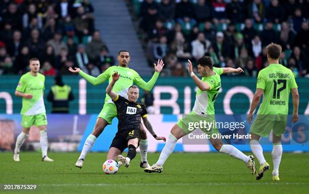 Marco Reus of Borussia Dortmund is challenged by Maxence Lacroix and Jonas Wind of VfL Wolfsburg during the Bundesliga match between VfL Wolfsburg...