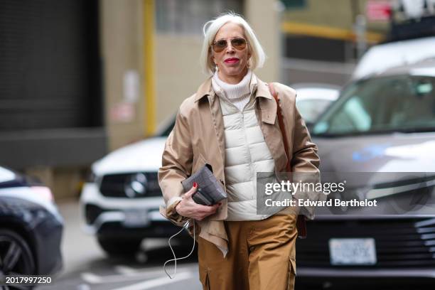 Guest wears aviator sunglasses, earrings, a beige leather jacket, a white turtleneck pullover in ribbed wool, a puffer jacket, brown wide leg cargo...