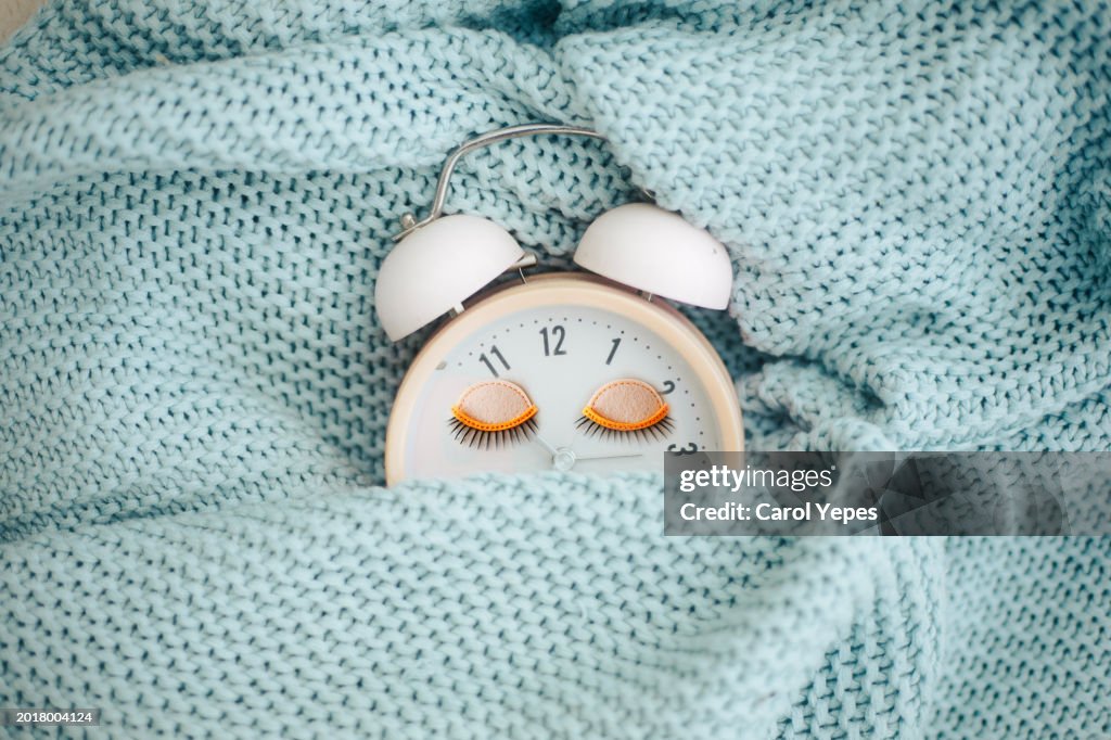 Pink alarm clock sleeping in bed