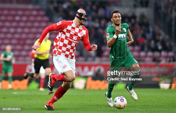 Ludovic Ajorque of 1.FSV Mainz 05 runs with the ball under pressure from Felix Uduokhai of FC Augsburg during the Bundesliga match between 1. FSV...