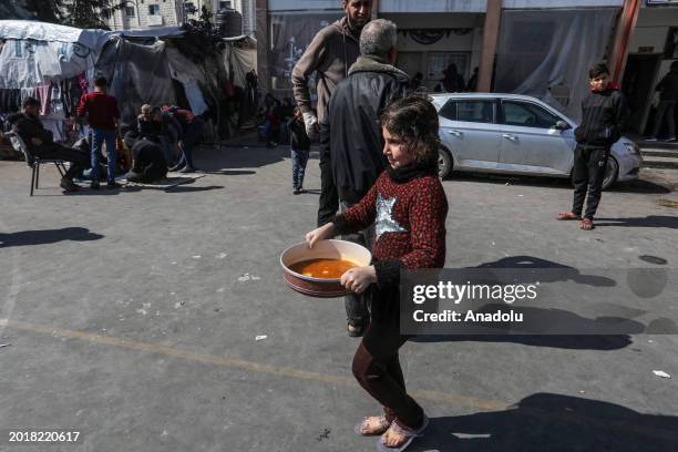Palestinian child carries pot as volunteers prepare hot meal for Palestinian families ,displaced to Southern Gaza due to Israeli attacks, in Rafah,...