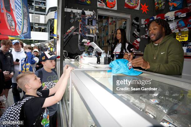 New Orleans Saints running back Alvin Kamara signs memorabilia for a NASCAR fan at a merchandise hauler on the midway during qualifying for the...