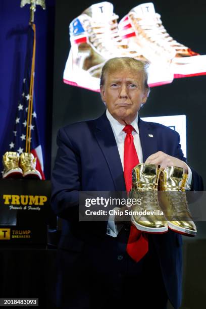 Republican presidential candidate and former President Donald Trump holds a pair of his new line of signature shoes after taking the stage at Sneaker...