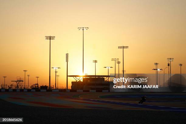 Prima Pramac Racing's Italian rider Michele Pirro is silhouetted against the setting sun as he steers his bike on the second day of the MotoGP...