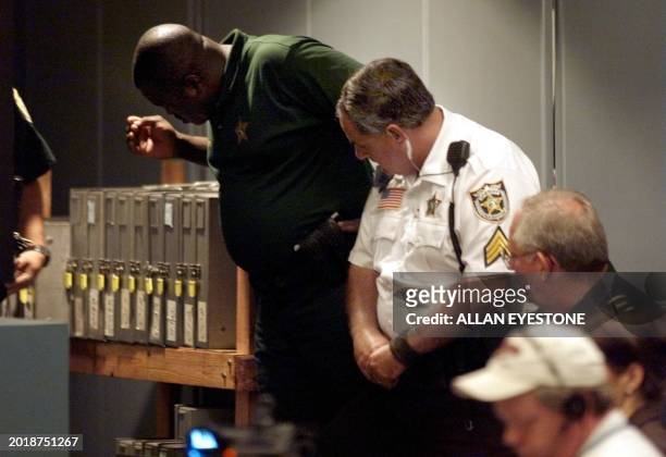 Palm Beach Sheriff officers look at a cart loaded with ballot boxes moments before the vote recount was reinitiated inside the Emergency Operations...