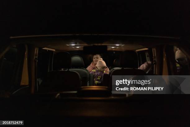 Woman sits in a minivan with a Ukrainian child after crossing the border from Belarus to Ukraine, in the Volyn region, on February 20 amid the...