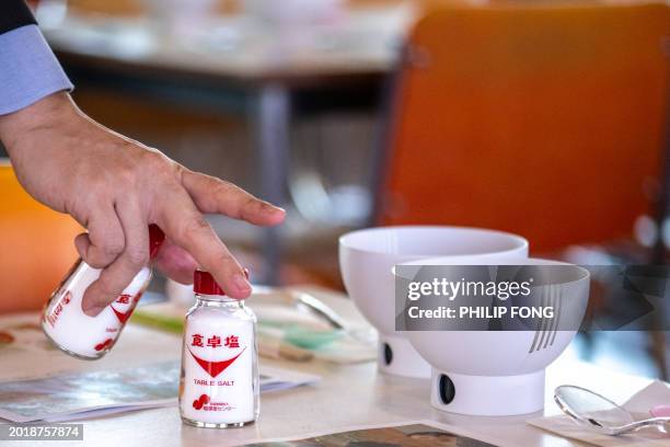 This picture taken on November 20, 2023 shows staff members preparing bottles of tablesalt with tableware, including electric bowls and spoons that...