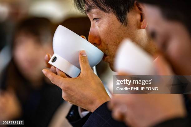 This picture taken on November 20, 2023 shows Odawara City employees tasting low-sodium foods by using electric bowls that enhance the salty taste of...