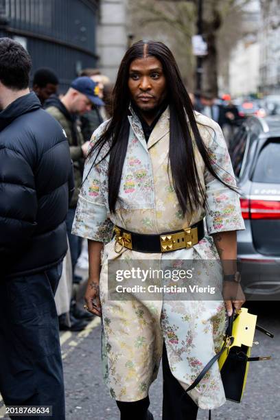 Law Roach wears Valentino belt, beige white dress with floral print, yellow Hermes bag outside Erdem during London Fashion Week February 2024 on...