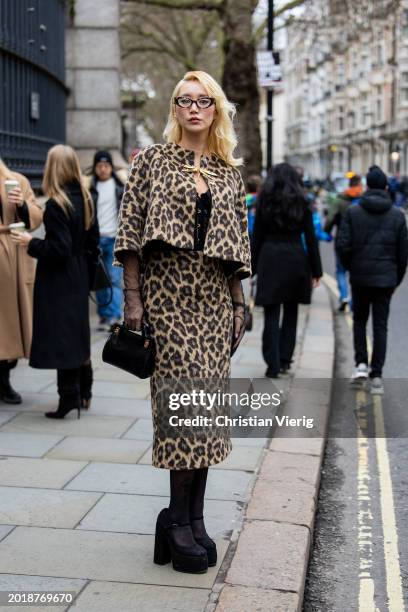 Betty Bachz wears cropped animal print leopard jacket, skirt, black bag, tights, glasses outside Erdem during London Fashion Week February 2024 on...