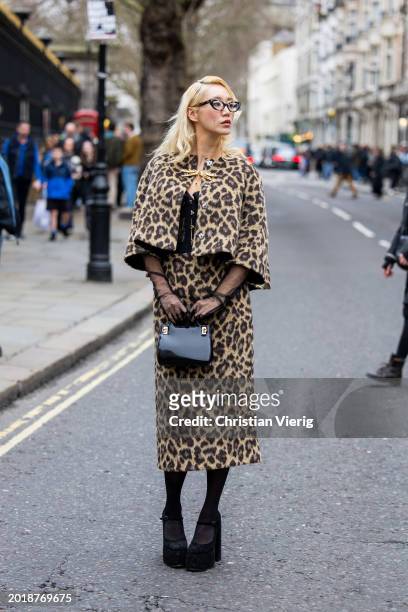 Betty Bachz wears cropped animal print leopard jacket, skirt, black bag, tights, glasses outside Erdem during London Fashion Week February 2024 on...