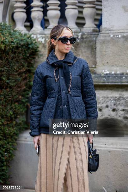 Guest wears blue quilted jacket, beige skirt, white pants outside Roksanda during London Fashion Week February 2024 on February 17, 2024 in London,...