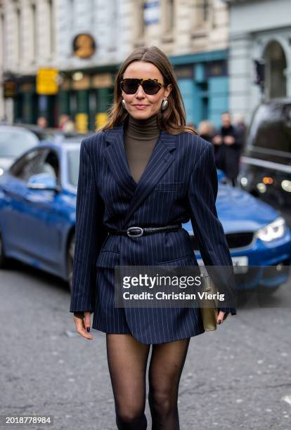 Chloe Street wears navy striped blazer, black belt, tights outside Erdem during London Fashion Week February 2024 on February 17, 2024 in London,...