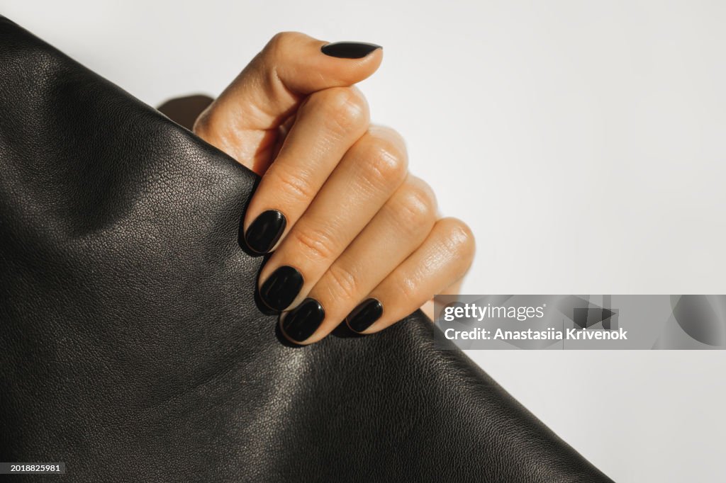Manicure on female hands with black nail polish.