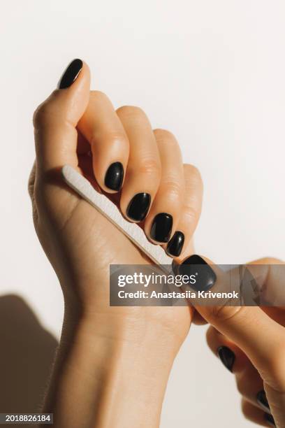 female hands saws with a nail file and shaped her nails in nail salon. - painting fingernails stock pictures, royalty-free photos & images