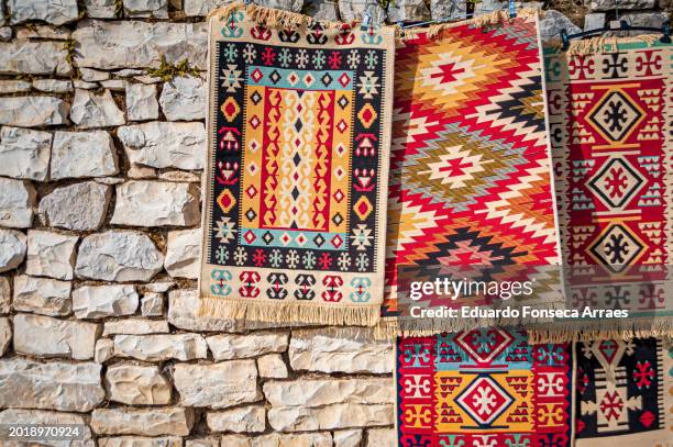traditional albanian tapestry hanging on the stone walls of the berat castle - albanian culture stock pictures, royalty-free photos & images