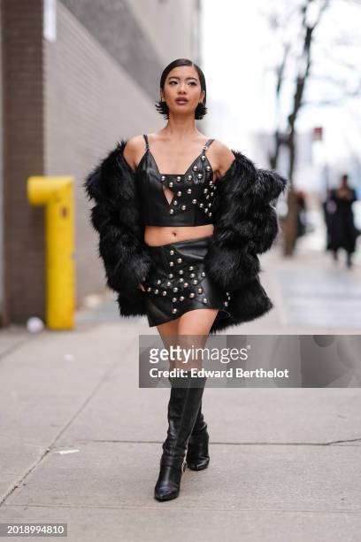 Guest wears lipstick and make-up made of mini pearls on the forehead, a black tank top made of black leather with silver pearls details, a black...