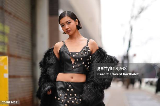 Guest wears lipstick and make-up made of mini pearls on the forehead, a black tank top made of black leather with silver pearls details, a black...