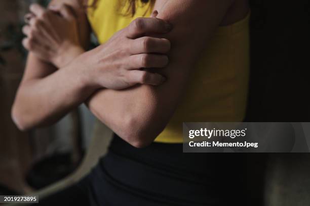 anxiety and itching. cropped image of nervous anxious woman sitting on sofa intching skin, bodys stress response, psychogenic itching - jucken stock-fotos und bilder