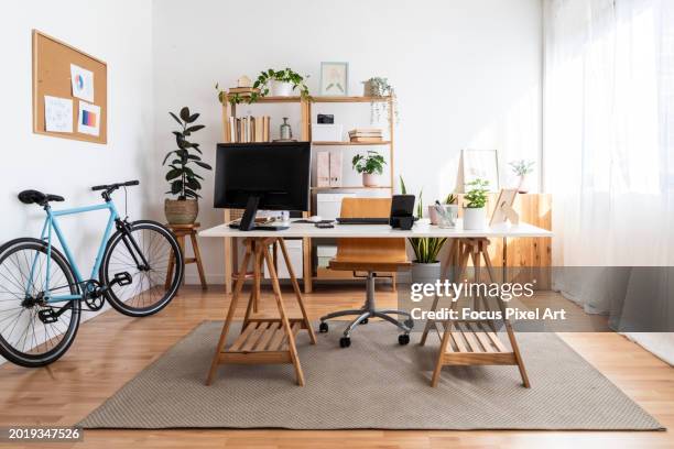 modern small office in a loft apartment with desk and bicycle - kantoorkamer stockfoto's en -beelden