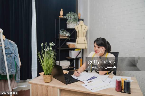 female designer with headache sitting at design studio - design studio woman chinese laptop stock pictures, royalty-free photos & images