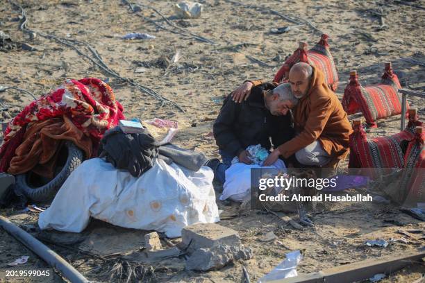 Man is comforted by another man as people inspect the damage to their homes following Israeli air strikes on February 18, 2024 in Rafah, Gaza....