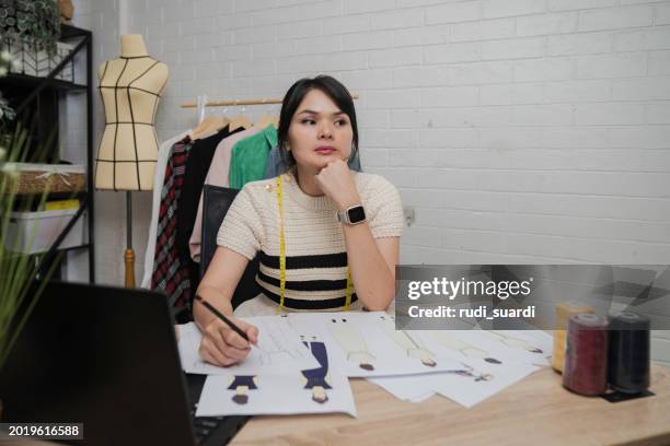 female designer with headache sitting at design studio - design studio woman chinese laptop stock pictures, royalty-free photos & images