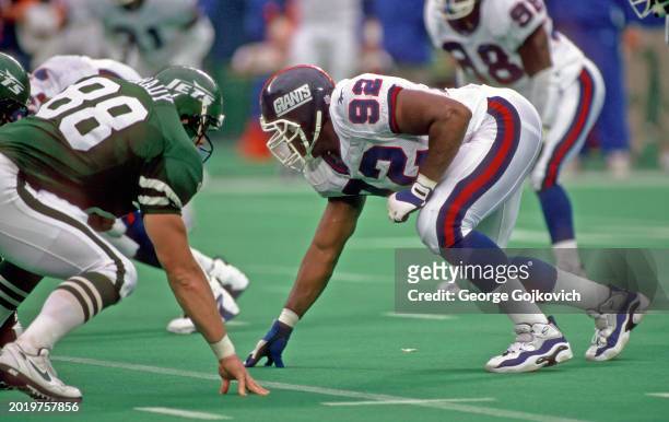 Defensive lineman Michael Strahan of the New York Giants looks across the line of scrimmage at tight end Kyle Brady of the New York Jets during a...