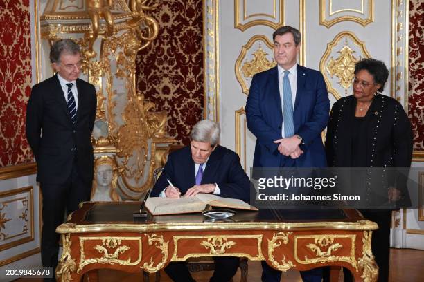 Former US secretary of state John Kerry signs the Bavarian government's guest book beside of MSC chairman Christoph Heusgen , Bavaria's state...