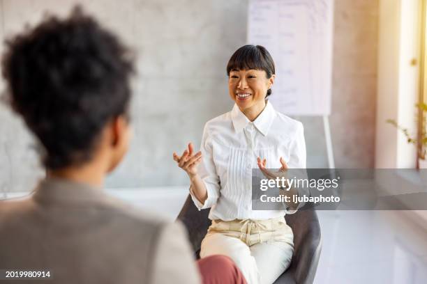 shot of a young woman having a therapeutic session with a psychologist - entrevista imagens e fotografias de stock