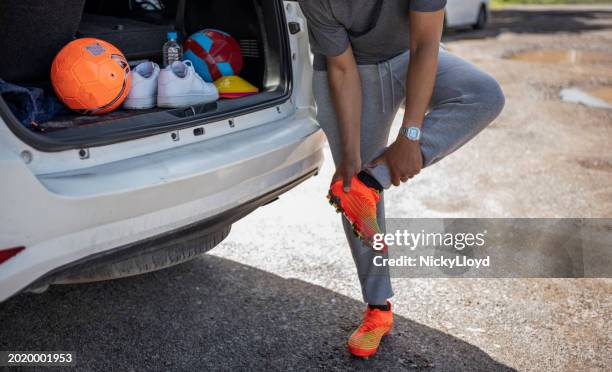 soccer player removing soccer shoes in the back of a car after practice session - south africa training session stock pictures, royalty-free photos & images