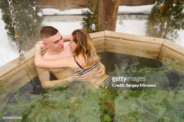 affectionate young couple sharing a tender moment in a snowy outdoor hot tub - wire binding stock pictures, royalty-free photos & images