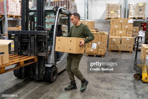man working at warehouse, carrying cardboard box - stacking boxes stock pictures, royalty-free photos & images