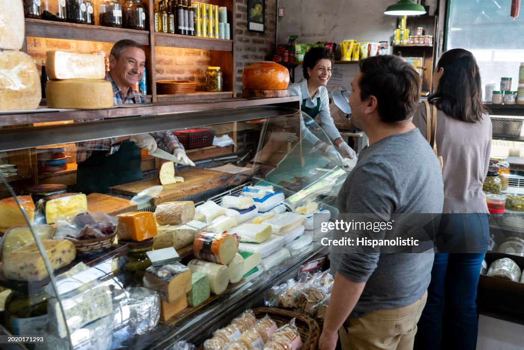 Customers buying products at a charcuterie with the help of friendly sales people