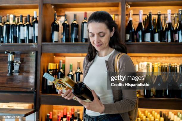 caucasian woman at the winery buying two bottles of wine - argentina wine stock pictures, royalty-free photos & images