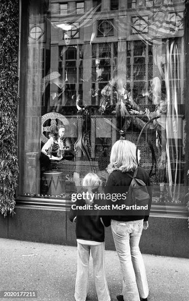 View, from behind, of a woman and a child as they look at a window display outside of Sak's Fifth Avenue department store on 5th Avenue , New York,...