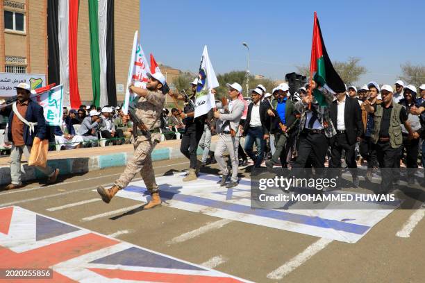 Students recruited into the ranks of Yemen's Huthi group parade, walking over Israeli and British flags on the ground, during a rally in support of...