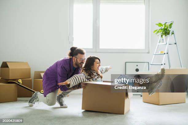 young couple couple having fun and playing with cardboard box at new home - new girlfriend stock pictures, royalty-free photos & images