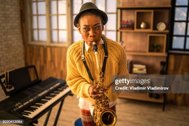 a woman is concentrating on playing her saxophone - pork pie stock pictures, royalty-free photos & images