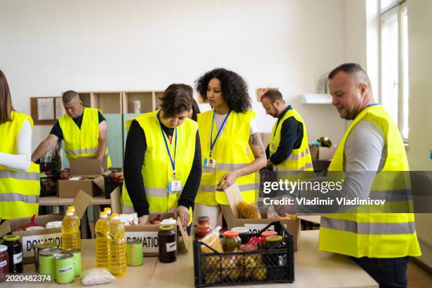 volunteers distributing food contributions into boxes - soup kitchen stock pictures, royalty-free photos & images