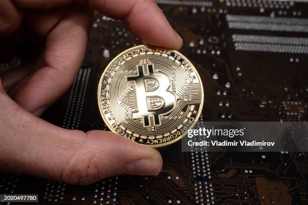 human hand holding a bitcoin - printed circuit b stock pictures, royalty-free photos & images