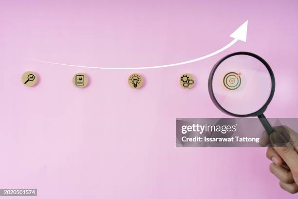 achieve business success with a magnifier focusing on a target icon, representing planning and leadership. - digital dartboard stock pictures, royalty-free photos & images