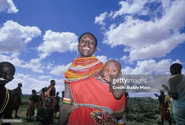 Young Samburu woman wearing beaded necklace jewelry, holds her young child at a Samburu village near Samburu National Wildlife Refuge in Kenya,2000....