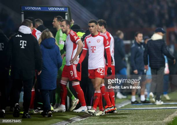 Harry Kane and Jamal Musiala of Bayern Munich walk off the pitch after the game was interrupted during the Bundesliga match between VfL Bochum 1848...