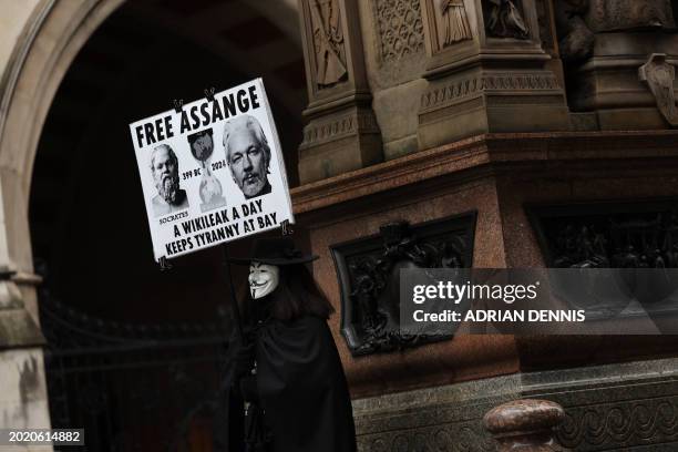 Demonstrator holds a placard reading "A Wikileak a day keeps Tyranny at Bay" as they protest outside of the Royal Courts of Justice, Britain's High...