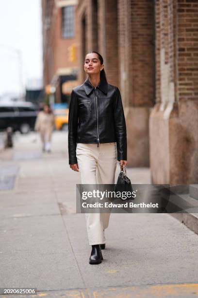 Guest wears a black leather jacket , white denim jeans pants , black leather shoes , a leather bag, outside Proenza Schouler , during New York...