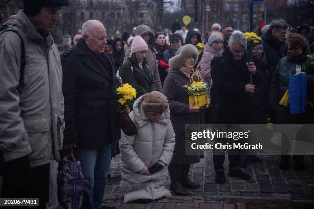 People pray during a minute's silence at plaques showing the portraits of late Euromaidan activists at the memorial site of the Heavenly Hundred...