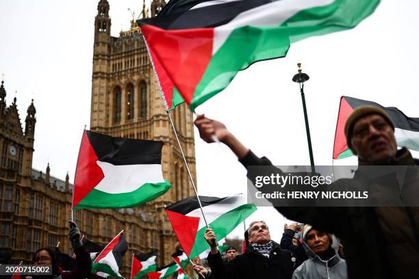 Demonstrators wave Palestinian flags as they protest in Parliament Square in London on February 21 during an Opposition Day motion in the the House...