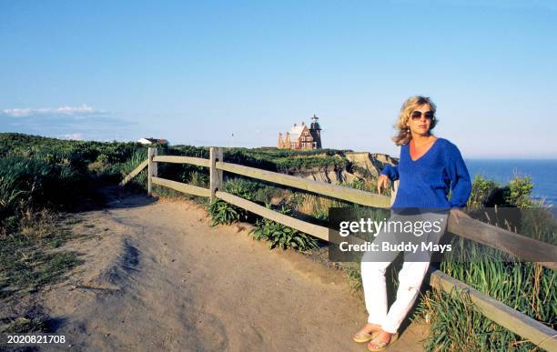 Woman visitor stands near Southeast Light lighthouse on Block Island, Rhode Island, 2011. .